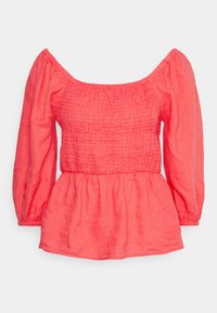 Blusa de linho coral com decote elástico à prova de ombros e mangas longas com volume. Corpo franzido que leva a uma barra arredondada.