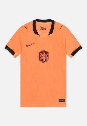 Lyse orange kortærmet fodboldtrøje med sort krave og ærmekanter, med et løveemblem og Nike-logo foran.