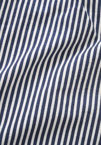 Gros plan sur un tissu à rayures verticales bleu marine et blanches avec des détails de texture subtils.