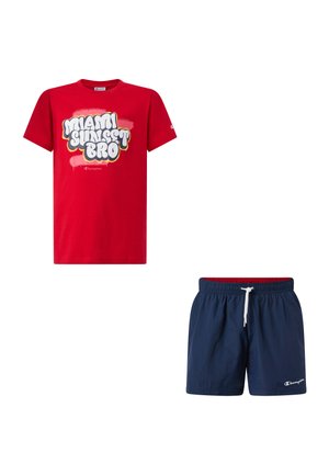 Maglietta rossa a maniche corte con testo "Miami Sunset Bro" abbinata a pantaloncini da bagno blu navy con coulisse bianca e logo Champion.