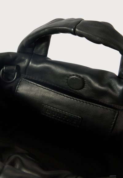Μαύρη δερμάτινη τσάντα σε στρογγυλό σχήμα, με δύο κοντές λαβές και κούμπωμα με κλιπ. Περιλαμβάνει εσωτερική τσέπη και ετικέτα μάρκας.