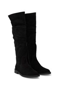 Stivali neri in suede sopra il ginocchio con suola piatta, dotati di una cerniera laterale e un design leggermente slouchy. Texture liscia e silhouette semplice.