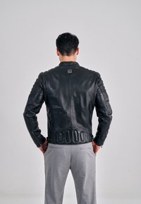 Czarna skórzana kurtka z prążkowanymi akcentami na ramionach i dopasowanym krojem. Posiada zamki przy mankietach oraz logo na kołnierzu.