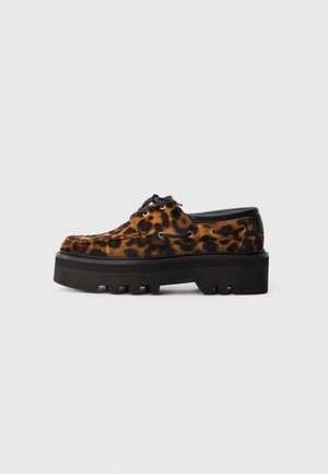 Sapatos de camurça com padrão de leopardo, sola grossa preta e atacadores; apresentam ilhós de metal e parte superior texturizada para um detalhe adicional.