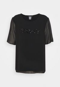 Haut noir DKNY avec des manches courtes et transparentes. Il présente un col rond et des lettres en sequins noirs sur le devant. Texture lisse et légèrement transparente.
