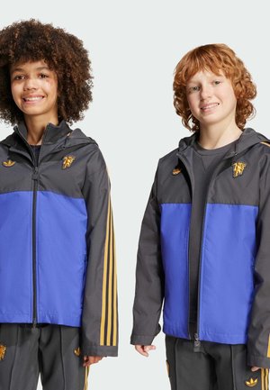 Chaquetas de cremallera coloridas con un torso azul y mangas negras, con rayas amarillas en los brazos y acentos de logo.