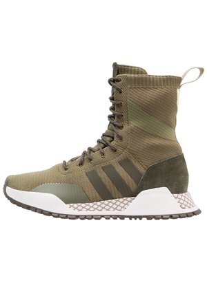 Wysokie buty sportowe w kolorze oliwkowej zieleni wykonane z dzianiny, z przodu sznurowane, z trzema ciemnymi paskami, teksturowaną podeszwą i pętelką na pięcie.