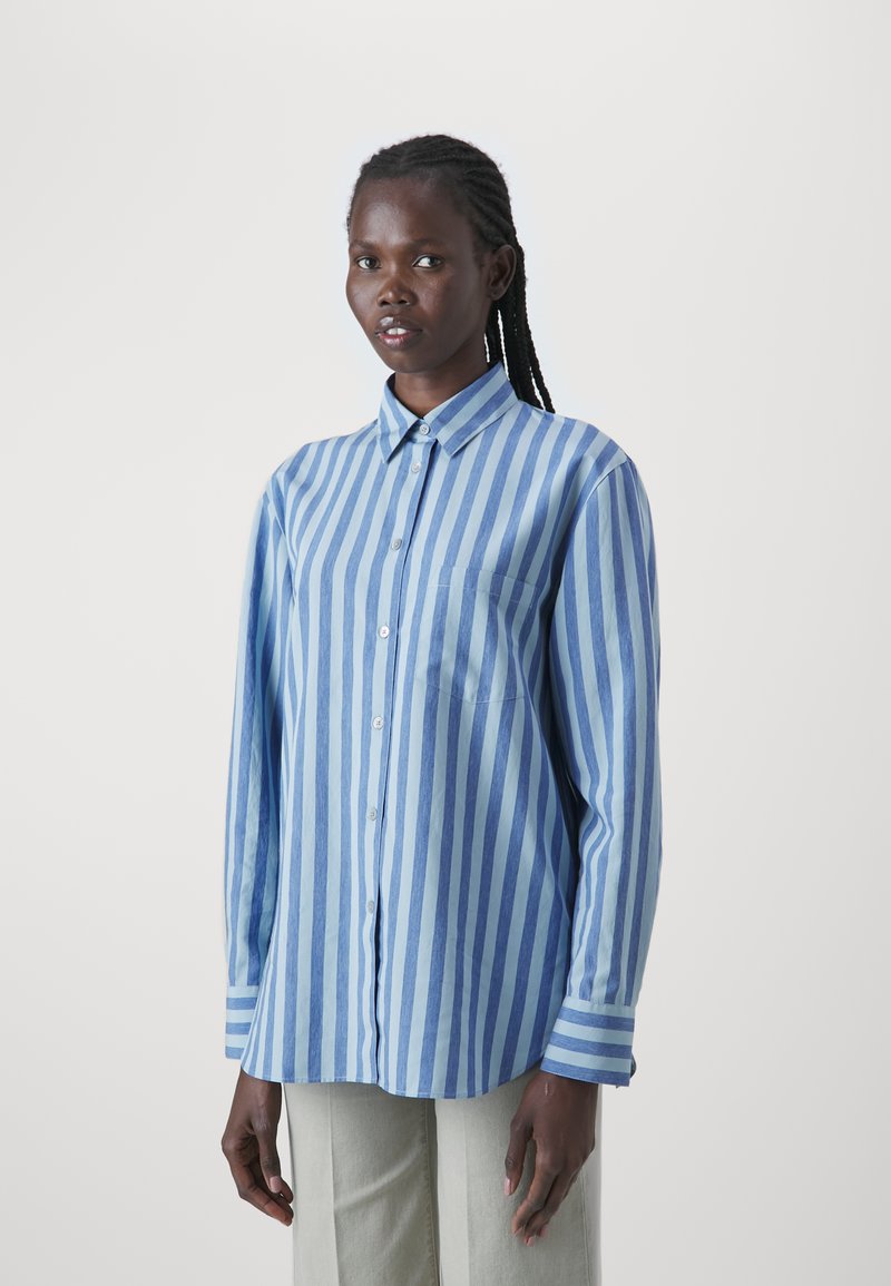 Langärmliges Button-Down-Hemd in blauen und hellblauen vertikalen Streifen, aus weichem Stoff, mit einer einzelnen Brusttasche und einem kragenbelegten Halsausschnitt.