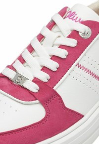 Baskets blanches avec des accents en daim rose, lacets ronds blancs et un détail de logo en métal. Design perforé sur le bout pour une meilleure respirabilité.