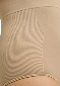 Beige high-waisted shapewear met ribbelstructuur en gladde zijkanten; heeft naadloze randen voor comfort en een comfortabele pasvorm.