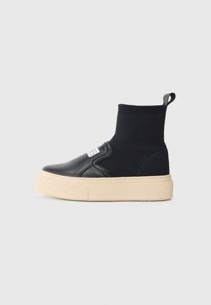 Svarta ankelsneakers med en texturerad stickad ovandel och släta läderdetaljer, med en tjock beiges gummisula och en dragflik bak.