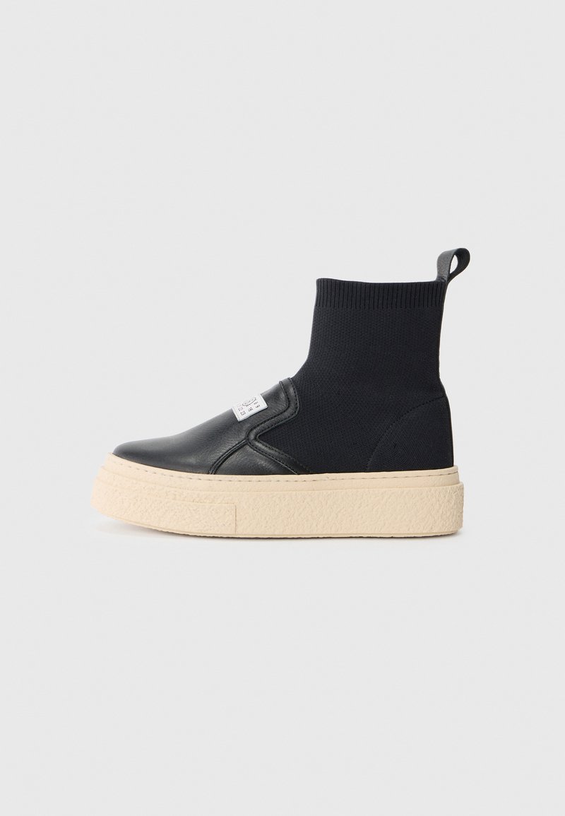 Svarta ankelsneakers med en texturerad stickad ovandel och släta läderdetaljer, med en tjock beiges gummisula och en dragflik bak.