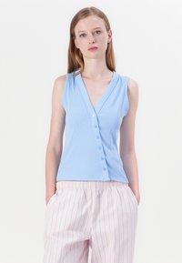 Top sin mangas de color azul claro con escote en V y seis botones en el frente, tejido texturizado; combinado con pantalones a rayas rosas.