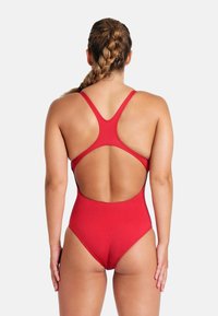 Maillot de bain une pièce rouge avec un design à dos nageur, dos ouvert, texture lisse et emmanchures medium, sans matériel visible ni motifs.