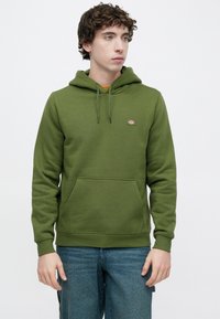 Φούτερ με κουκούλα σε ελιά πράσινο, κατασκευασμένο από μείγμα βαμβακιού, με μπροστινή τσέπη, κουκούλα με κορδόνι και μικρό λογότυπο στο στήθος. Απλός σχεδιασμός.