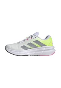 Zapatillas deportivas blancas con rayas grises, acentos en amarillo neón y una parte superior de malla texturizada. Cuenta con una entresuela blanca gruesa y una suela negra.