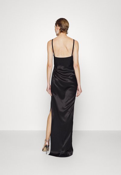 Fekete selyem estélyi ruha vékony pántokkal, illeszkedő felsőrésszel és combmagas oldalszárral. Simaság jellemzi, folyékony sziluettel.