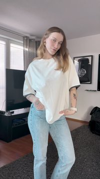 Weißes, übergroßes T-Shirt mit kurzen Ärmeln und rundem Ausschnitt, kombiniert mit hellblauen Skinny Jeans. Minimalistisches Design, keine sichtbaren Muster.