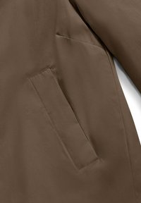 Bruin buitenstof met een gladde textuur en een nette afwerking, met een verborgen zijzak en minimale stikdetails.