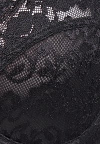 Zwarte kanten lingerie met een gestructureerde mesh overlay, voorzien van bloemenpatronen en ingewikkelde stiksels door de stof.