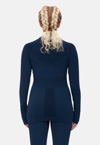 Marinblå långärmad träningsöverdel med en figurnära design, texturerad insida och sömlös konstruktion med subtila panelaccenter.