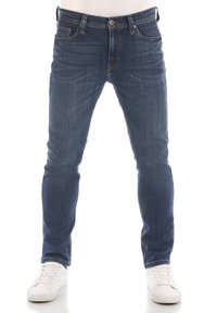 Vaqueros de denim azul ajustados con un lavado desvanecido, cinco bolsillos y cremallera. Presenta costuras en contraste y herrajes metálicos.