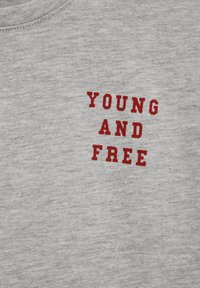 Tela gris con texto rojo que dice "JOVEN Y LIBRE" en una fuente negrita, en mayúsculas, centrado en el material.