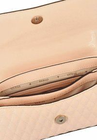 Beige gewatteerde handtas met magnetische sluiting, met zicht op binnenvak met ritssluiting en stoffen voering bedrukt met herhaaldelijk "GUESS" logo.