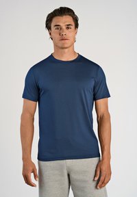 Marineblå kortærmet t-shirt i et let, tekstureret materiale med rund halsudskæring og afslappet pasform, parret med grå joggingbukser.
