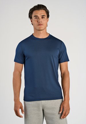Marineblå kortærmet t-shirt i et let, tekstureret materiale med rund halsudskæring og afslappet pasform, parret med grå joggingbukser.