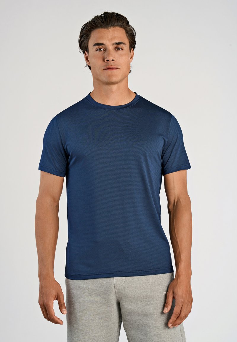 Marineblå kortærmet t-shirt i et let, tekstureret materiale med rund halsudskæring og afslappet pasform, parret med grå joggingbukser.
