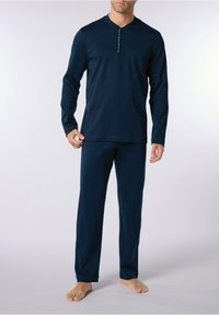 Set di pigiama a maniche lunghe di colore blu navy realizzato in tessuto morbido, con collo Henley a bottoni e vestibilità comoda. Le tasche sui pantaloni non sono visibili.
