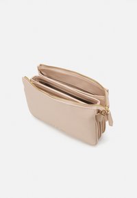Vaaleanbeige vetoketjullinen clutch-laukku, jossa on sileä pinta, kaksi sisätaskua, kultaiset metalliosat ja minimalistinen muotoilu.