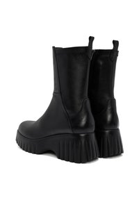 Bottes noires mi-mollet avec des semelles larges crantées, des tirants à l'arrière et des fermetures éclair sur le côté, présentées de manière angulaire arrière sur un fond blanc.