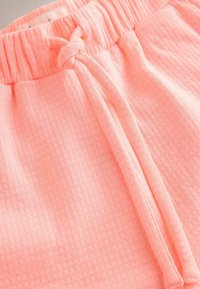 Shorts roses texturés avec une taille élastique et un cordon de serrage. Dotés d'un tissu respirant avec un petit motif de points en relief.