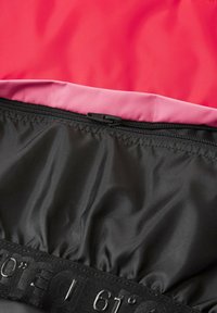Tessuto impermeabile nero con una superficie liscia, foderato con materiali rosa e rossi. Presenta una zip lungo la parte superiore con un'etichetta di marchio.