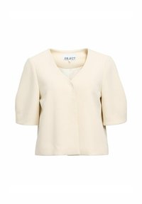 Haut à manches courtes de couleur crème avec un décolleté en V, présentant une silhouette épurée et un tissu lisse, sans fermetures visibles.