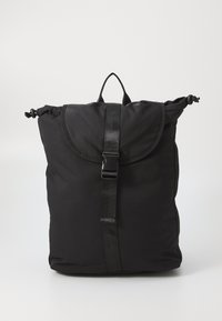 Black nylon backpack with a rounded top, roll-top closure, adjustable strap, and a central buckle. Smooth texture with minimalistic design.