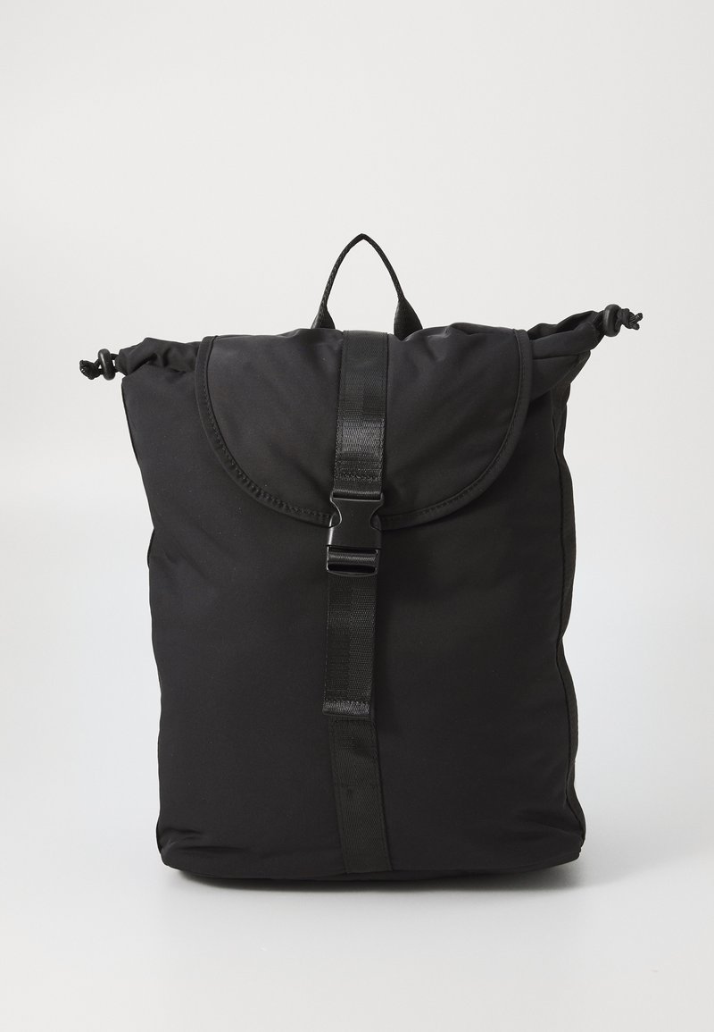 Black nylon backpack with a rounded top, roll-top closure, adjustable strap, and a central buckle. Smooth texture with minimalistic design.