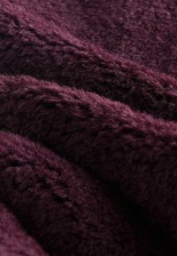 Hladká, textúrovaná tkanina v hlbokej burgundskej farbe, ktorá predvádza mäkké, chlpové vlákna prepletené s jemným leskom a subtilnými vzormi.