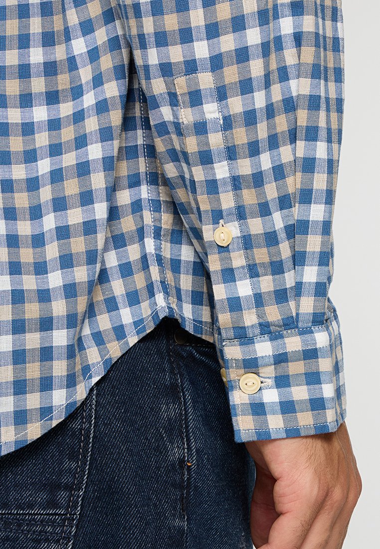 Geruit overhemd in blauwe en beige tinten, met een button-down kraag, lange mouwen en een afgeronde zoom. De stof lijkt lichtgewicht en gestructureerd te zijn.