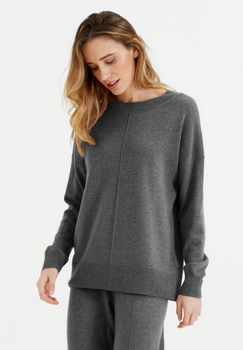 Pull en tricot gris à col large, avec des manches longues et un ourlet côtelé. Présente un design simple avec une texture lisse et un minimum de détails.