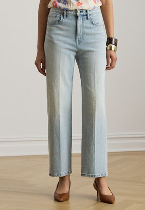 Világoskék, magas derekú, egyenes szárú farmer, virágos felsővel, barna magassarkúval, valamint vastag arany- és teknősbéka mintás karkötőkkel viselve.