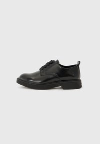 Chaussures en cuir noir à lacets avec un bout arrondi, semelle texturée et petit talon ; présentent des coutures minimales et une languette à l'arrière.