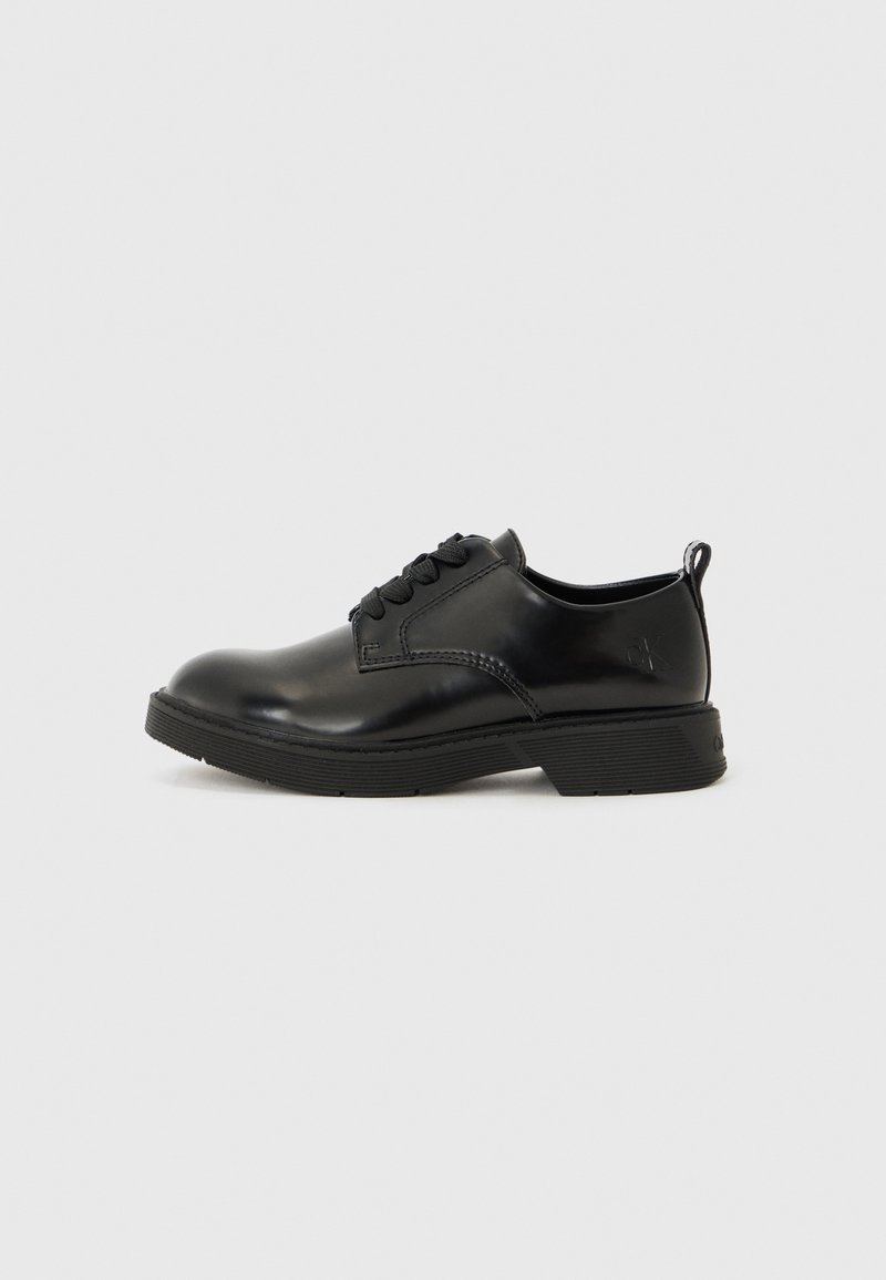 Chaussures en cuir noir à lacets avec un bout arrondi, semelle texturée et petit talon ; présentent des coutures minimales et une languette à l'arrière.