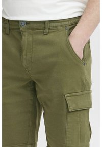 Pantalones cargo en color verde oliva, elaborados con una mezcla de algodón duradera, que cuentan con múltiples bolsillos, cierre de botón y un diseño de corte relajado.