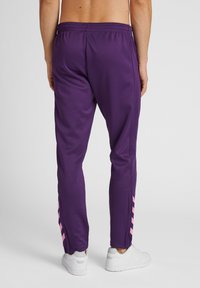 Paarse sportbroek met een relaxte pasvorm, voorzien van roze zijkanten, elastische tailleband en een soepele, lichtgewicht stofstructuur.