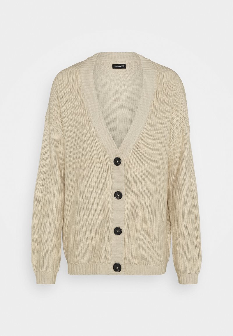 Cardigan beige en maille avec un col en V profond, des manches longues, des poignets et un ourlet côtelés, et quatre gros boutons noirs sur le devant.