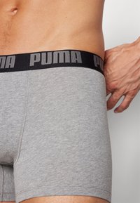 Gray boxer shorts made of soft fabric, featuring a black elastic waistband with embossed "PUMA" logo in gray.