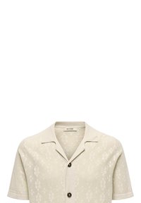 Maglietta lavorata a maglia a maniche corte in un beige chiaro con un motivo geometrico, colletto aperto e bottoni neri. Tessuto leggero e strutturato.